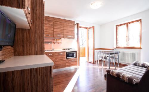a kitchen with wooden cabinets and a living room at CROSINA HOLIDAY - Residence Toli in Ledro