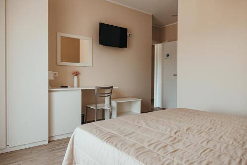 - une chambre avec un lit, une table et une télévision dans l'établissement Affittacamere Mira Sinni, à Episcopia