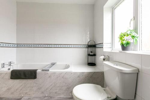 a white bathroom with a toilet and a bath tub at Kime Contractor & Holiday Home in Lincolnshire