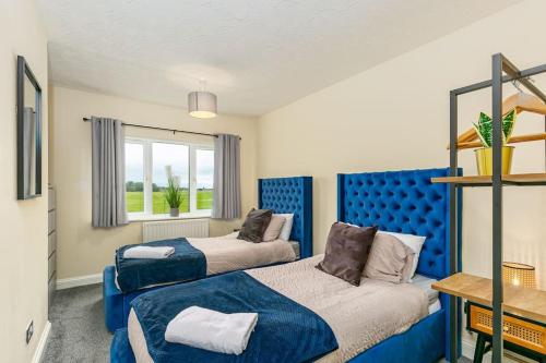 a bedroom with two beds and a blue headboard at Kime Contractor & Holiday Home in Lincolnshire