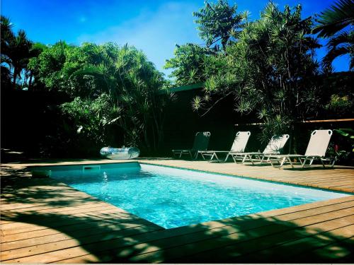 una piscina con due sedie e una terrazza in legno di Mabouya chez Villas Piment Café a Deshaies