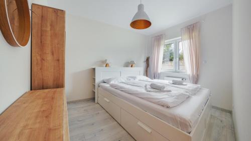 a white bedroom with a bed with a window at Apartamenty Sun & Snow Bursztynowa Polana in Ustka