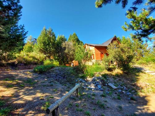 a house in the middle of a field with a fence at Las Retamas in Villa Pehuenia