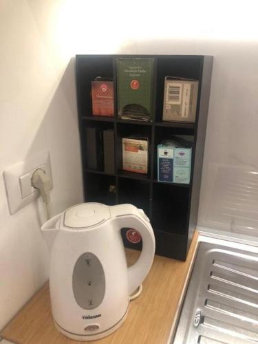 a tea kettle sitting on the floor next to a shelf at Villa Camilla Milano in Milan