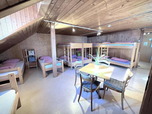 a room with a table and chairs and bunk beds at Jugendherberge Hospental in Hospental