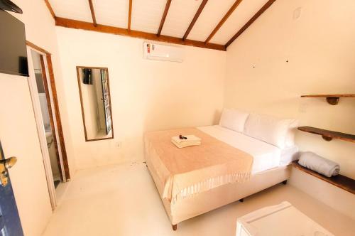 a small bedroom with a bed and a mirror at Pousada Vilarejo in Caraíva