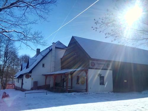 ein Gebäude im Schnee mit der Sonne dahinter in der Unterkunft Penzion U dvojice in Nové Město na Moravě