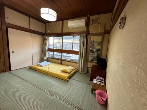 Cette petite chambre comprend un lit et une fenêtre. dans l'établissement Numazu Ikyuuan 沼津一休庵, à Numazu