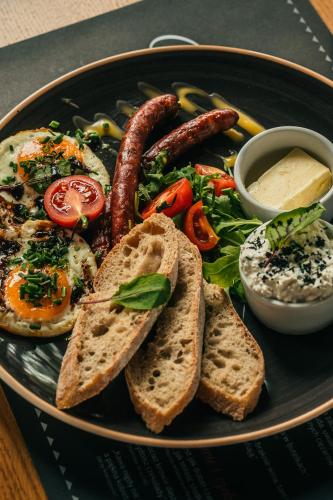 a plate of breakfast food with sausage bread and toast at Villa T Apartments & SPA in Zakopane