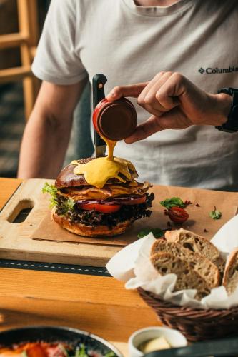 a person is pouring sauce on a hamburger at Villa T Apartments & SPA in Zakopane