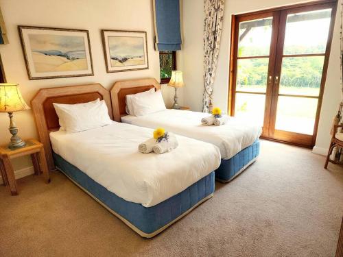 2 Betten in einem Hotelzimmer mit Blumen darauf in der Unterkunft Villa P12 - Selborne Golf Estate in Pennington