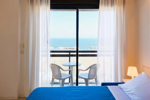 a bedroom with a bed and a view of the ocean at Rex Residence Hotel in Cattolica