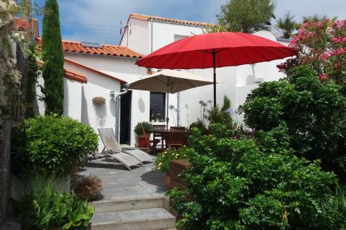 une maison avec un parasol rouge et une terrasse dans l'établissement Maison de pêcheur aux Sables dOlonne Entre Océan, à Les Sables-dʼOlonne
