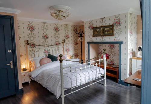 a bedroom with a white bed with floral wallpaper at Anne Boleyn’s Escape in Deal