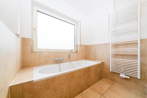 a bathroom with a bath tub and a window at G & L Hotel Dortmund in Dortmund