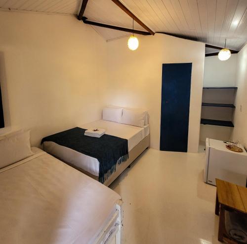 a room with two beds and a blue door at Pousada Vilarejo in Caraíva