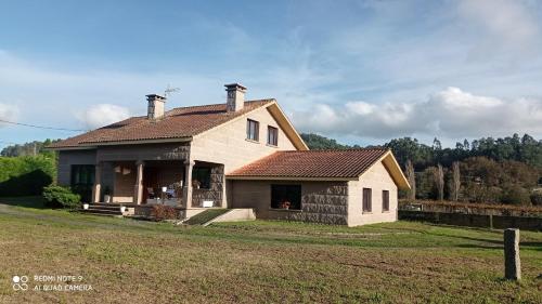 a house with a roof on a grass field at A Eira de Salvador in Portas