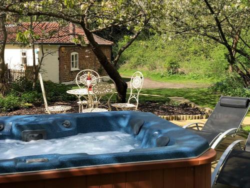 a hot tub in a yard with a table and chairs at Gamekeepers Cottage, hot tub & open fire. in Gaywood