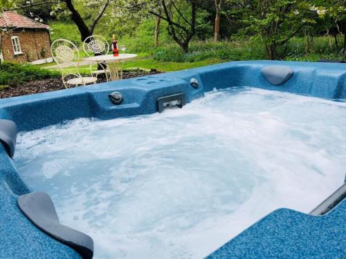 a jacuzzi tub in a yard with a table at Gamekeepers Cottage, hot tub & open fire. in Gaywood