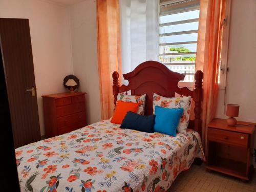 a bedroom with a bed with colorful pillows and a window at Villa Flora, escapade champêtre in Petit-Canal
