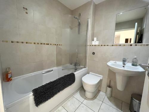 a bathroom with a white tub and a toilet and a sink at Plush Apartment 2 bed for Business and Pleasure in Wakefield