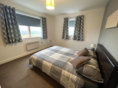 a bedroom with a bed and two windows at Plush Apartment 2 bed for Business and Pleasure in Wakefield
