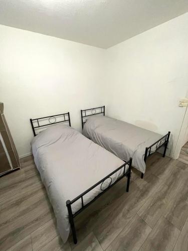 deux lits dans une chambre aux murs blancs et au parquet dans l'établissement Appartement 3 chambres à Troyes, à Troyes