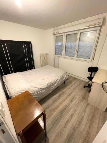 une chambre avec un lit et un bureau et deux fenêtres dans l'établissement Appartement 3 chambres à Troyes, à Troyes
