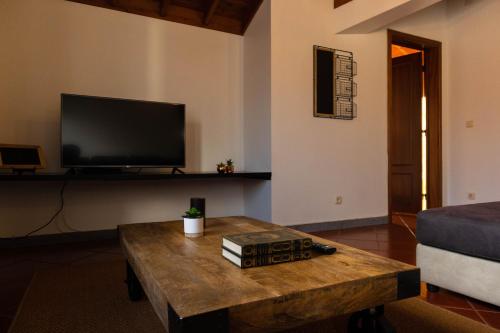 a living room with a coffee table and a flat screen tv at By the hill in Ribeira Grande