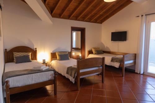 a hotel room with two beds and a tv at By the hill in Ribeira Grande