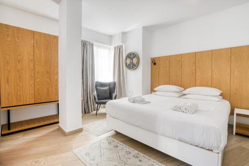 una camera con un grande letto bianco e una sedia di Elia Kolonaki Luxury Apartments ad Atene