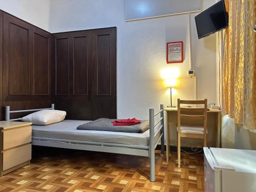 a bedroom with a bed and a desk and a television at Kecskeméti Rooms in Budapest