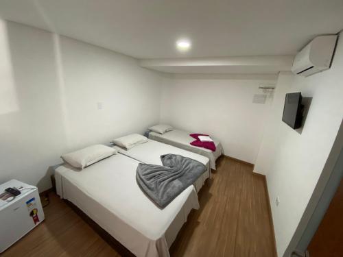 Duas camas num quarto com paredes brancas e pisos de madeira em Pousada Vila Barboza - Próxima ao Thermas Water Park em Águas de São Pedro