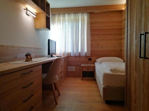 a bedroom with a bed and a desk with a television at Casa Mariella - Apartment with garden in Tesero