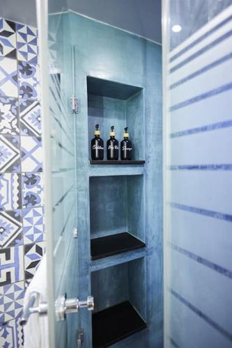 a bathroom with four bottles of alcohol on shelves at A3_Aplotaria Architect's Apartment in Chios