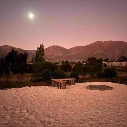 a picnic table in the sand with mountains in the background at Fogones del Valle in Las Rojas