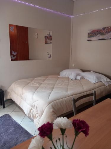 um quarto com uma cama e uma mesa com flores em Studio near University of Thessaly em Lárissa