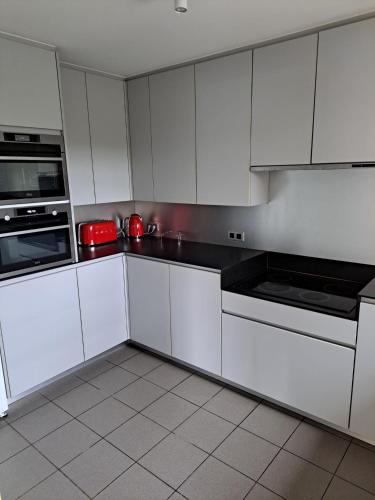 a white kitchen with white cabinets and appliances at Villa SandNest in Koksijde