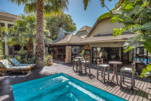 an outdoor patio with a swimming pool and a house with a palm tree at Onse Khaya Lodging and Conferencing in Port Elizabeth