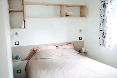 a small bedroom with a bed with white sheets at Mobil Home XXL 4 chambres - Camping Les Relarguiers in Beauvezer