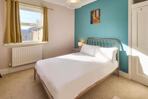 a bedroom with a white bed with a blue wall at Host & Stay - Westbrook Road in Margate