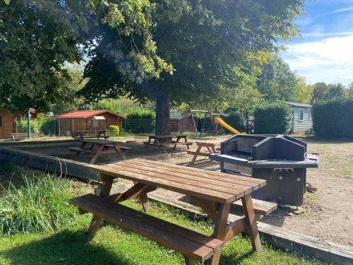 - un groupe de tables de pique-nique et un grill dans un parc dans l'établissement Camping la Faloise, à Angicourt