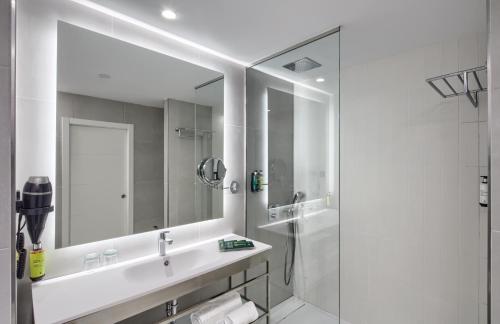 a white bathroom with a sink and a mirror at Sercotel Rosaleda Málaga in Málaga