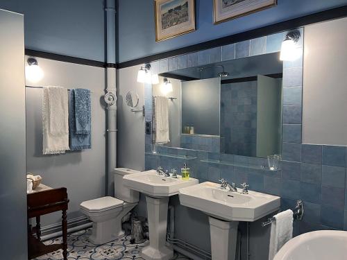 a bathroom with two sinks and a toilet and a mirror at Château de La Rivière in Pontgouin