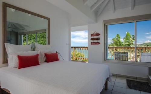 a bedroom with a large white bed with red pillows at Saint Barth Villa 2 in Saint-Jean