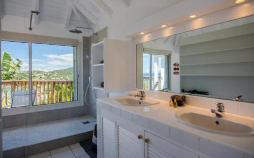 un bagno con due lavandini e un grande specchio di Saint Barth Villa 2 a Saint-Jean