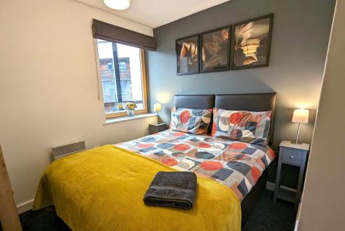 a bedroom with a bed with a yellow comforter at Gorgeous Modernised City Centre Apartment in Coventry