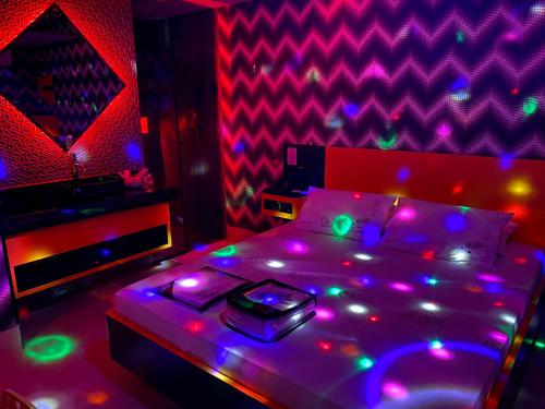 - une chambre dotée d'un lit avec des lumières violettes et vertes dans l'établissement Motel Deslize Curitiba, à Curitiba