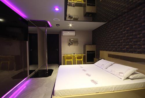 a bedroom with a large bed with purple lights at Motel Deslize Curitiba in Curitiba