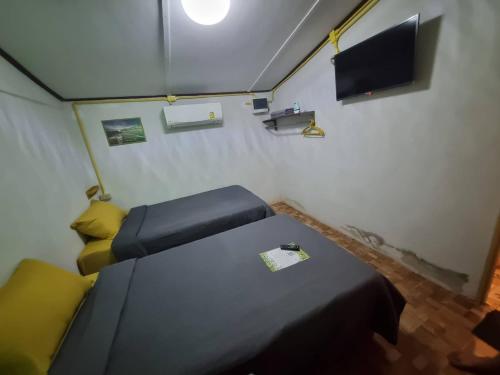 a small room with two beds and a tv at บ้านสวน คุณอารี รีสอร์ท in Ban Khok Takhro
